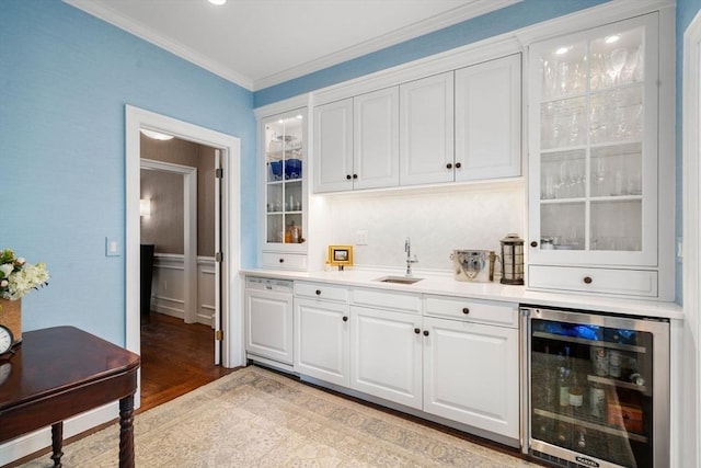 bar with crown molding, light wood-style flooring, a sink, wet bar, and beverage cooler