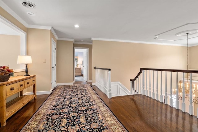 hall featuring visible vents, ornamental molding, wood finished floors, an upstairs landing, and a notable chandelier