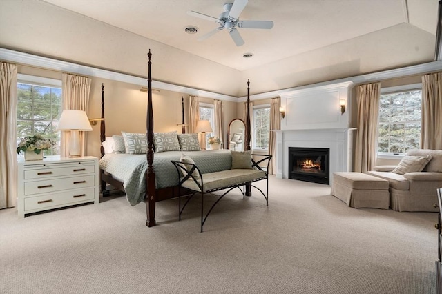 bedroom featuring a glass covered fireplace, light carpet, visible vents, and multiple windows