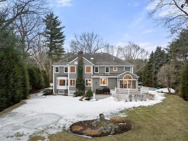 snow covered rear of property with a chimney