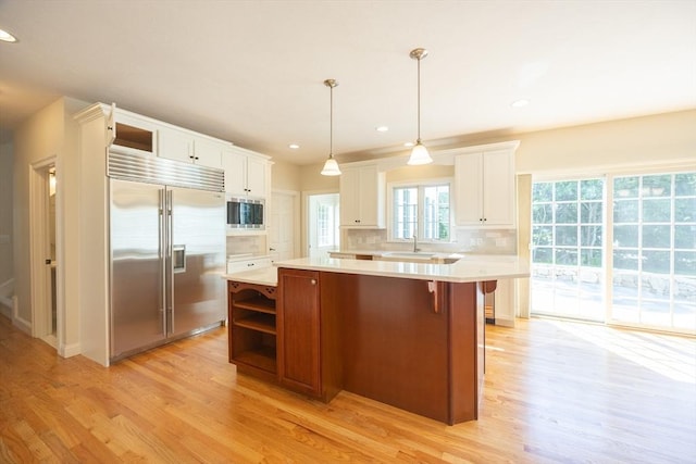 2 Pine Ridge Ln, Mattapoisett, MA 02739 - kitchen with built in appliances, light countertops, open shelves, a kitchen island, and light wood finished floors