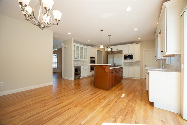 2 Pine Ridge Ln, Mattapoisett, MA 02739 - kitchen featuring built in appliances, wine cooler, a chandelier, white cabinetry, and a kitchen island