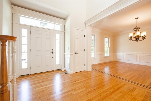 2 Pine Ridge Ln, Mattapoisett, MA 02739 - foyer entrance with a chandelier, light wood-style flooring, ornamental molding, a decorative wall, and a wainscoted wall