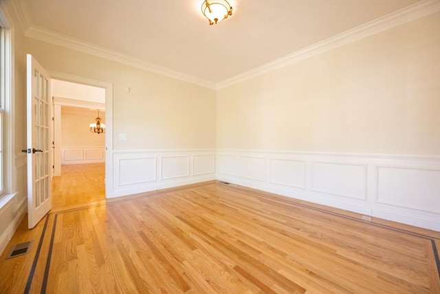 2 Pine Ridge Ln, Mattapoisett, MA 02739 - empty room with a chandelier, crown molding, light wood-style flooring, wainscoting, and a decorative wall