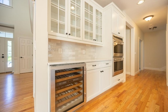 2 Pine Ridge Ln, Mattapoisett, MA 02739 - indoor dry bar with wine cooler, double oven, light wood-style flooring, decorative backsplash, and baseboards