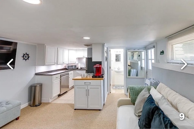 kitchen featuring light carpet, appliances with stainless steel finishes, white cabinets, and butcher block countertops