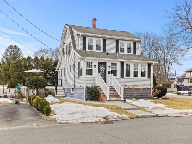 view of front of house with roof with shingles and a chimney