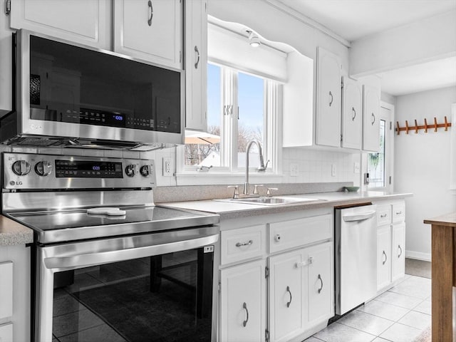 kitchen with a sink, backsplash, appliances with stainless steel finishes, and light countertops