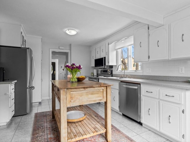 kitchen with a sink, stainless steel appliances, white cabinets, and light tile patterned floors