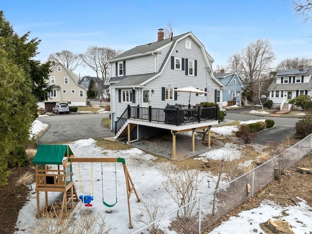 back of property featuring a playground, fence, a residential view, a gambrel roof, and roof with shingles