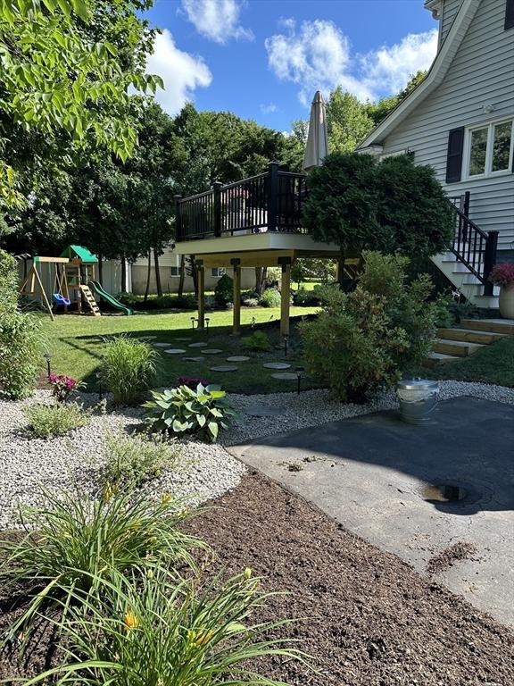 view of home's community featuring stairs, a playground, a lawn, and a wooden deck