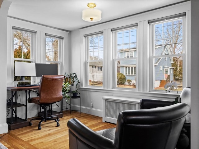 office area with baseboards, wood finished floors, and radiator heating unit