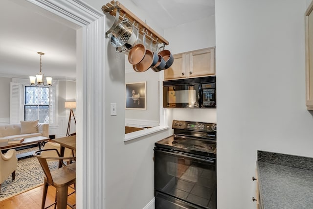 kitchen with ornamental molding, black appliances, light brown cabinets, and a notable chandelier