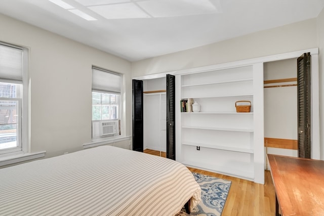 bedroom featuring cooling unit, multiple windows, and light hardwood / wood-style floors