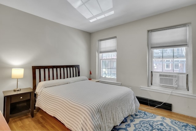 bedroom with a skylight, multiple windows, wood-type flooring, and cooling unit