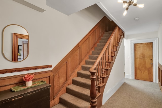 stairs with a chandelier and carpet flooring