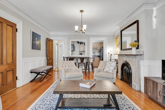 living room with sink, an inviting chandelier, crown molding, and light hardwood / wood-style flooring