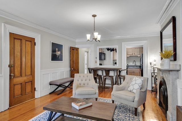 living room featuring crown molding, light hardwood / wood-style flooring, sink, and a notable chandelier