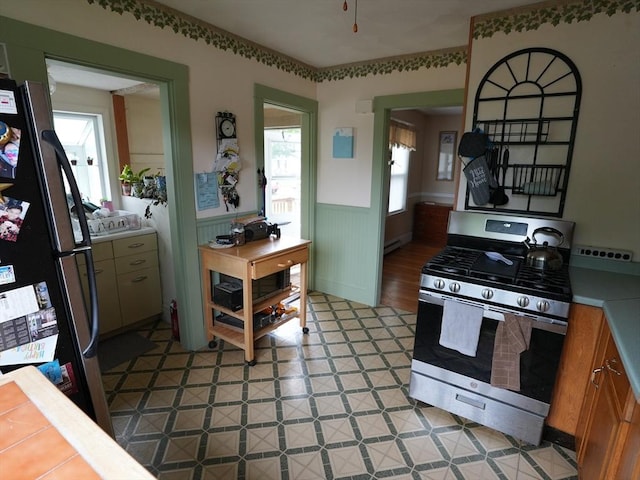 95AKA93 Lynnway, Revere, MA 02151 - kitchen featuring gas range, freestanding refrigerator, a wainscoted wall, tile counters, and baseboard heating