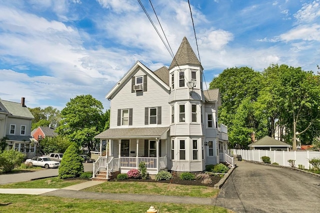 victorian home featuring a porch and fence