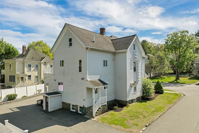 view of side of home featuring fence, a chimney, and a shingled roof