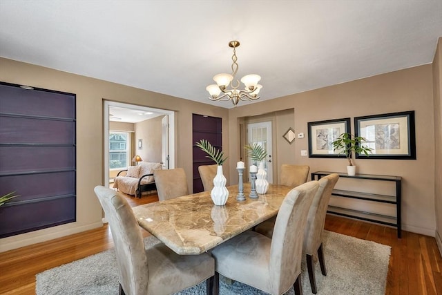 dining room with a chandelier, wood finished floors, and baseboards