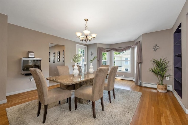 dining area with a chandelier, baseboards, wood finished floors, and baseboard heating