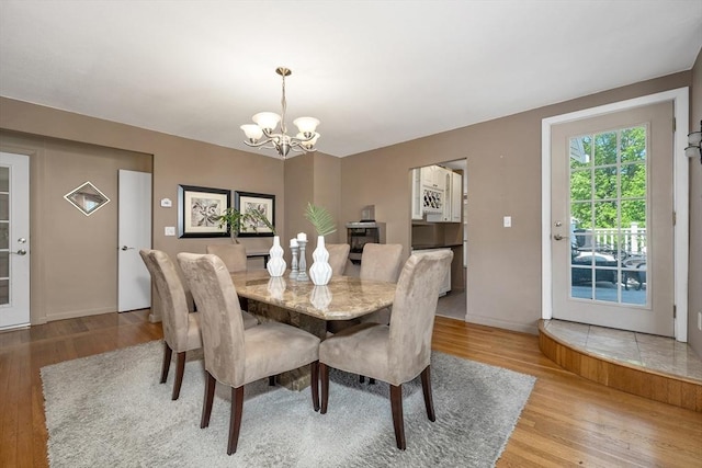 dining space with a chandelier, wood finished floors, and baseboards