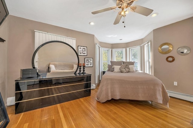 bedroom with a baseboard heating unit, wood finished floors, baseboards, ceiling fan, and recessed lighting