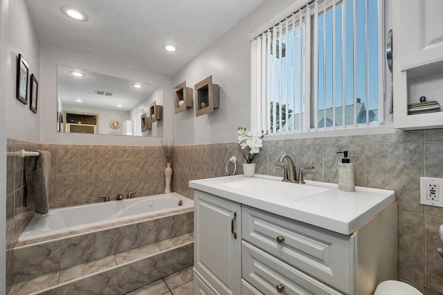 bathroom with tile walls, a bath, vanity, and recessed lighting
