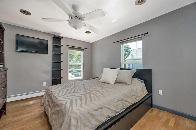 bedroom with baseboard heating, light wood-type flooring, and a ceiling fan