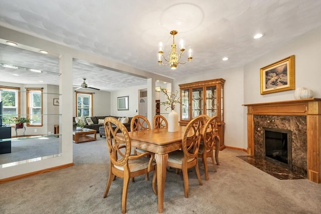 carpeted dining room with baseboards, a premium fireplace, a chandelier, recessed lighting, and a ceiling fan