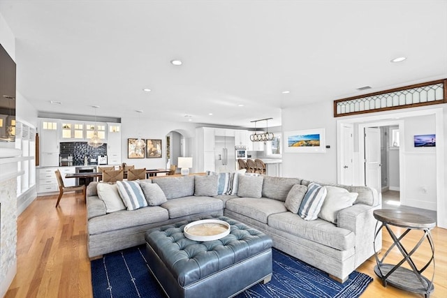 living room featuring recessed lighting, a notable chandelier, a healthy amount of sunlight, and light wood-type flooring