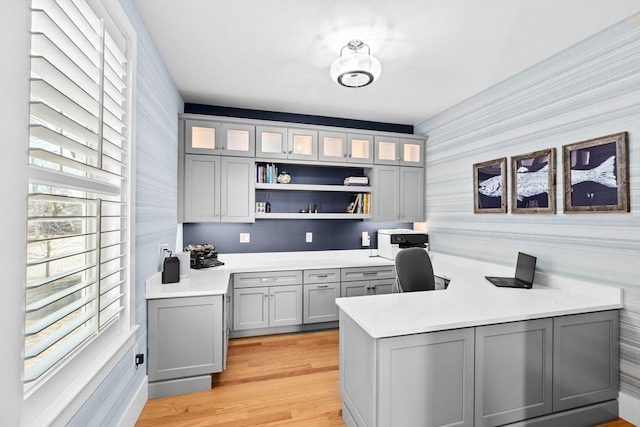 office with light wood-style floors and built in study area