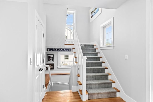 staircase with plenty of natural light, wood finished floors, and baseboards