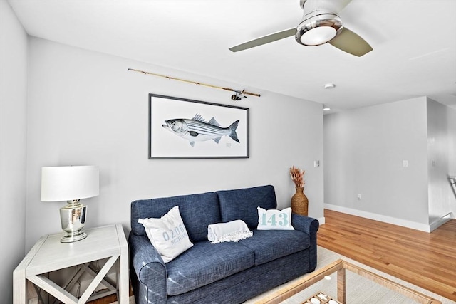 living area with baseboards, ceiling fan, and wood finished floors