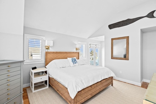 bedroom featuring baseboards, light wood-style floors, and vaulted ceiling