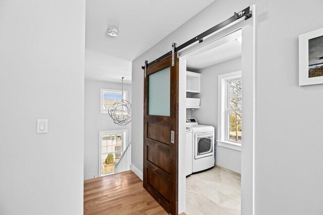 laundry room with baseboards, cabinet space, a barn door, a notable chandelier, and washer and clothes dryer