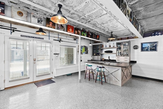 interior space with dark countertops, glass insert cabinets, a kitchen breakfast bar, speckled floor, and open shelves