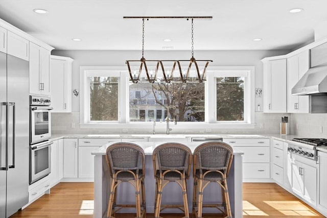 kitchen with a kitchen breakfast bar, light wood-style floors, appliances with stainless steel finishes, and a center island