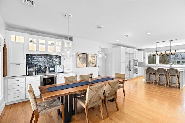 dining space with wine cooler, visible vents, recessed lighting, and light wood finished floors