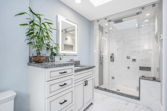 bathroom with vanity, a skylight, toilet, and an enclosed shower