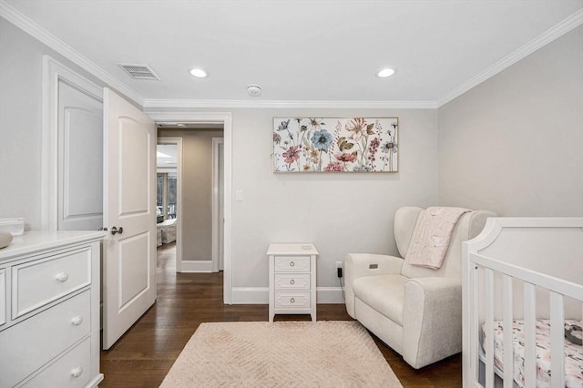 bedroom with dark hardwood / wood-style flooring, a nursery area, and crown molding