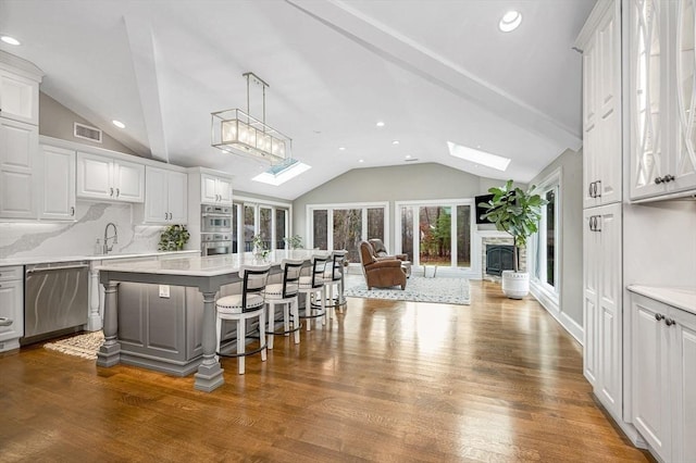 kitchen featuring a center island, backsplash, a kitchen breakfast bar, appliances with stainless steel finishes, and white cabinetry