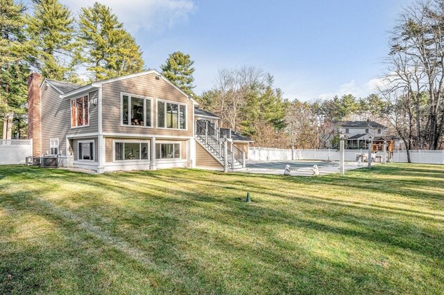 rear view of house with a lawn, cooling unit, and a fenced in pool