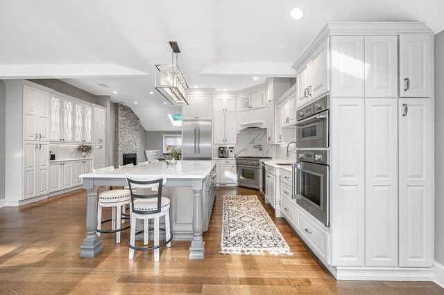 kitchen featuring pendant lighting, a center island, white cabinets, premium appliances, and a breakfast bar area