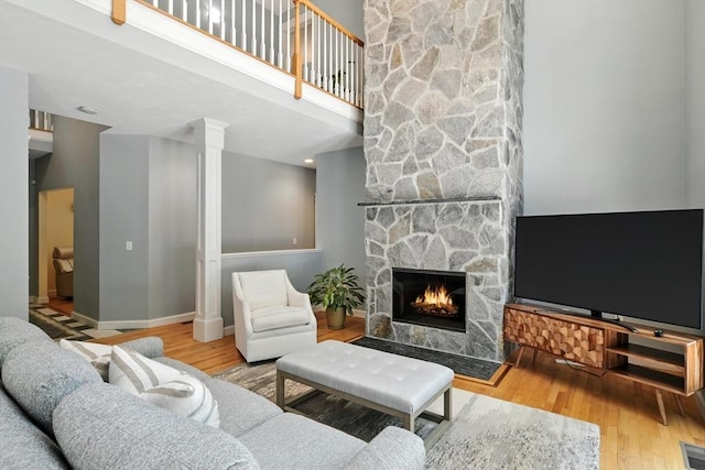 19 Hawthorn Rd, Amherst, MA 01002 - living area with wood finished floors, a stone fireplace, a towering ceiling, and decorative columns