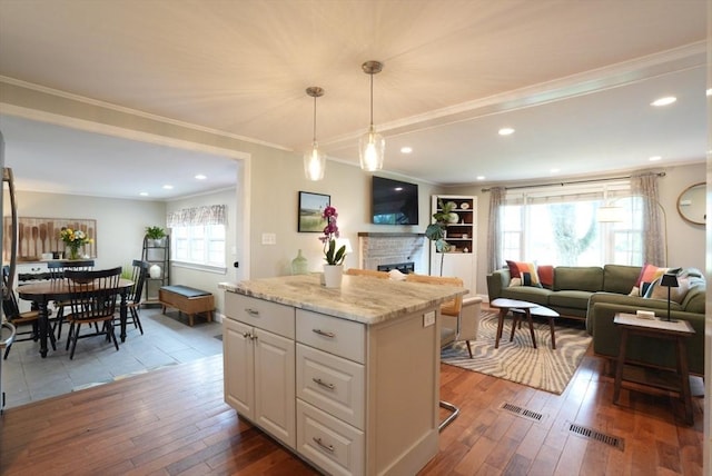 99 Edgehill Rd, Norwood, MA 02062 - kitchen featuring wood-type flooring, white cabinetry, crown molding, a fireplace, and open floor plan