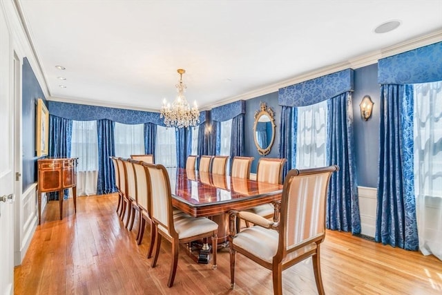 dining space featuring light wood-type flooring, an inviting chandelier, and ornamental molding