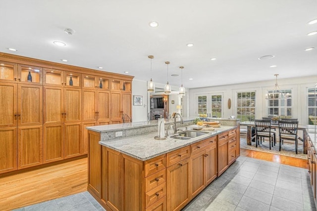 kitchen with a center island with sink, glass insert cabinets, brown cabinets, and a sink